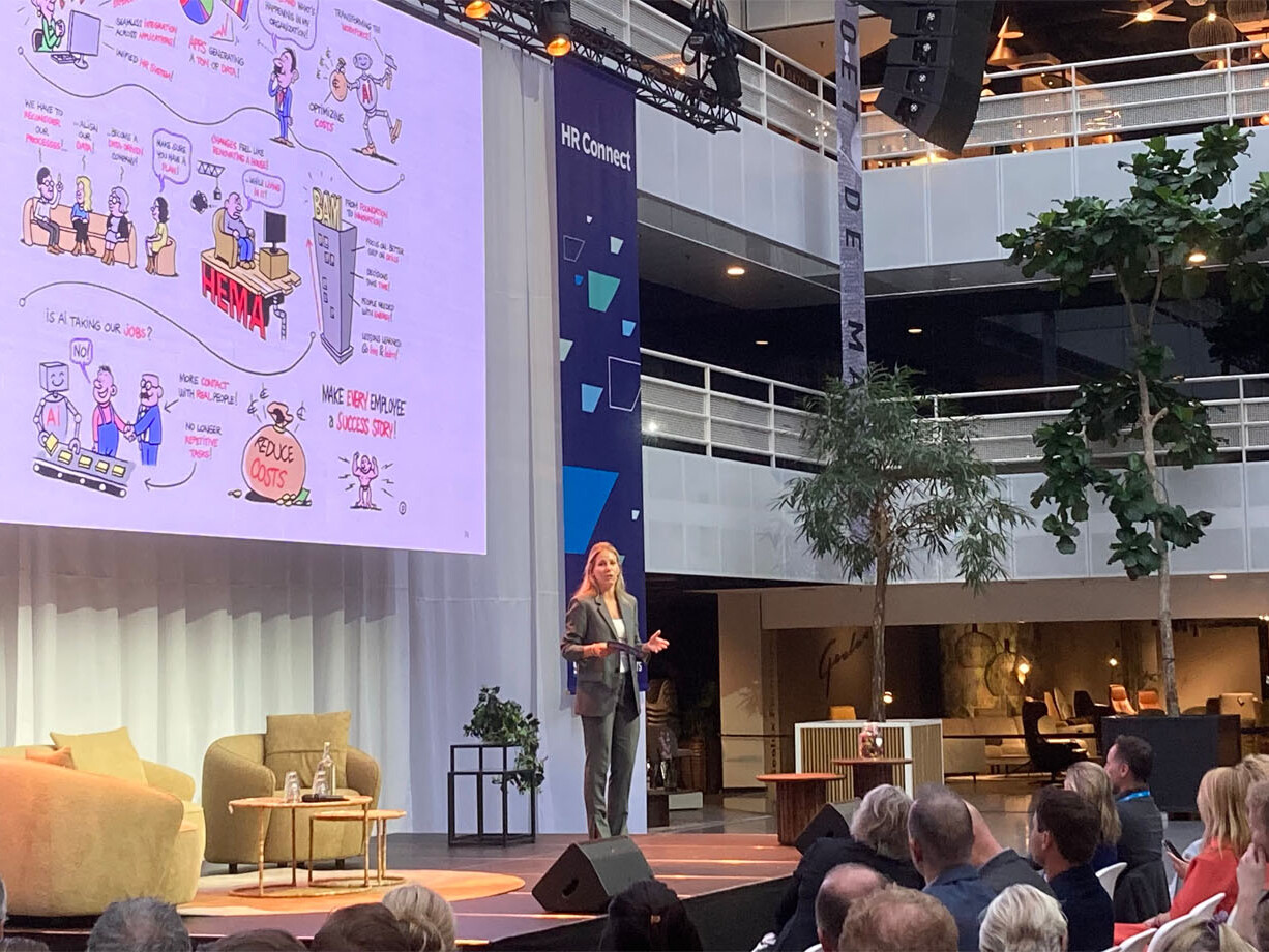 Vrouw presenteert op podium digitaal live tekenen op groot scherm