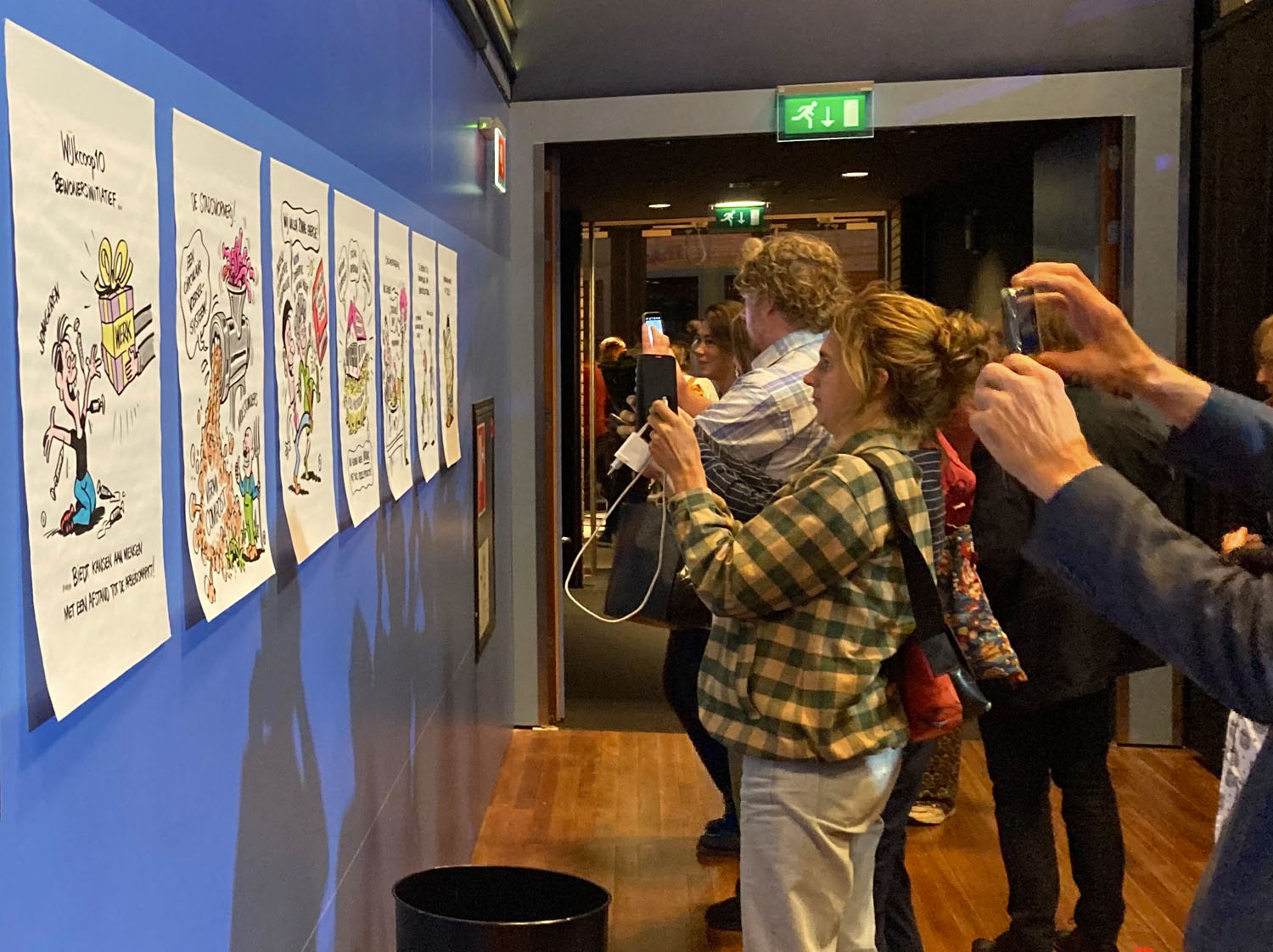 Bezoekers van symposium fotograferen tekeningen van zakelijk tekenaar aan de muur